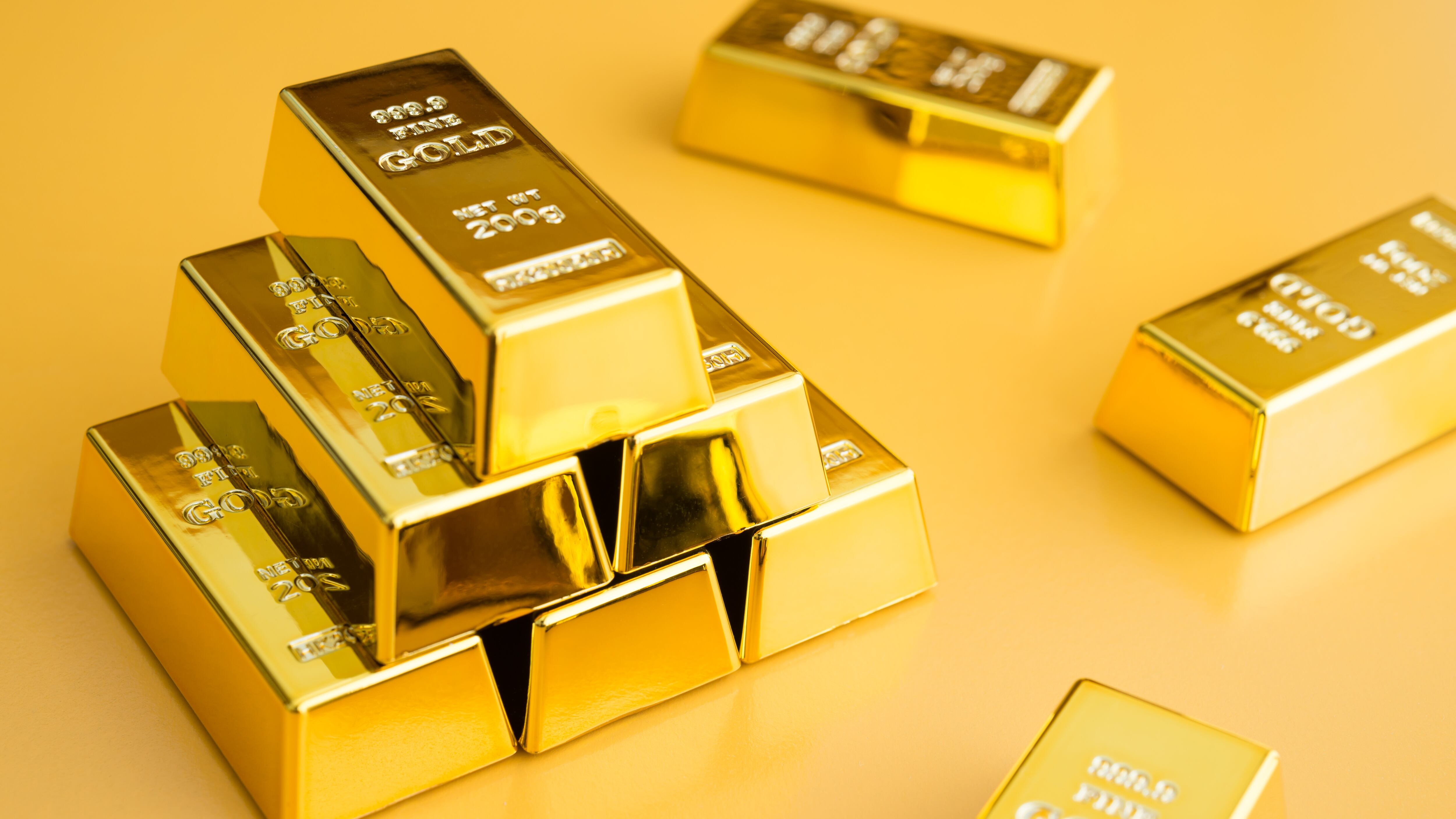 Gold bars or bullion stack on yellow background.