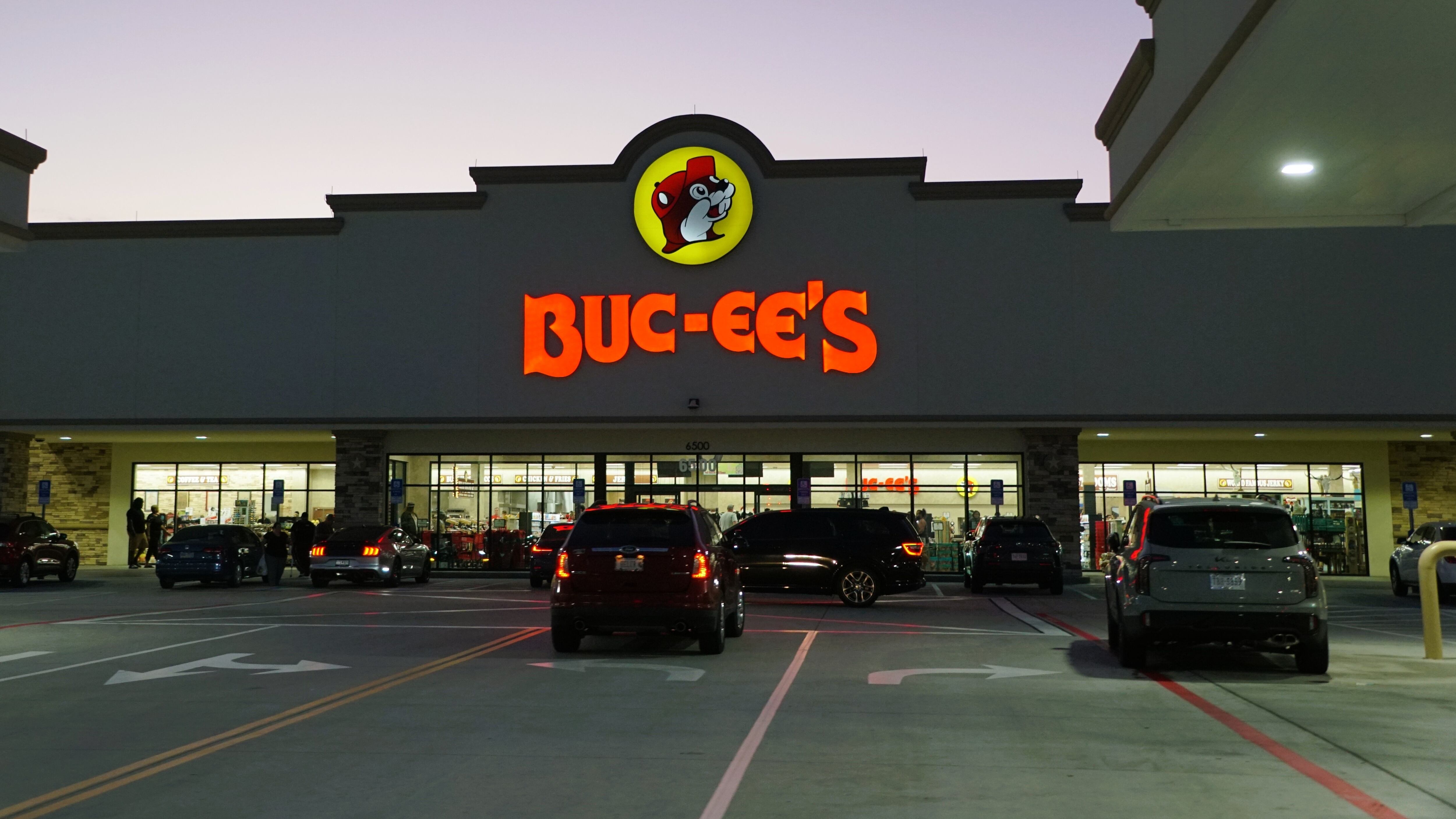 A busy parking lot of Buc-ee's store with their illuminated sign and logo at night